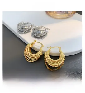 Close-up of retro U-shaped chain link earrings in gold and silver on a stone tray