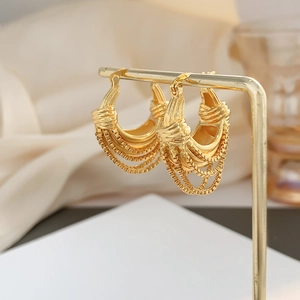 U-shaped gold chain hoop earrings with layered fringe detail on a luxury metal display stand