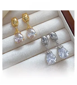 Detail of luxury teardrop zircon earrings in gold and silver finish on a jewelry box