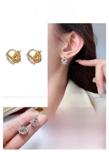 Macro detail of geometric triangle earrings with crystal baguette studs in gold plating
