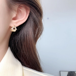Close-up of geometric triangle earring with baguette crystals on ear for daily luxury style