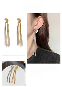 Detail of elegant gold and silver chain tassel earrings on model and close-up