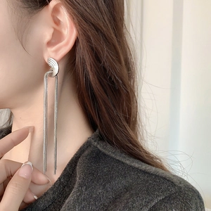 Detail view of silver tassel earrings with long snake chains on a female model