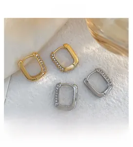 Detail view of rectangular gold and silver earrings with micro-set cubic zirconia stones