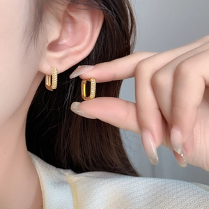 Macro detail of elegant 18K gold plated hoop earrings with micro-set cubic zirconia stones
