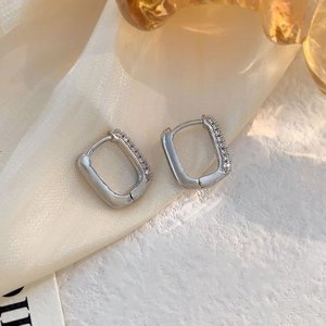 Elegant silver rectangular hoop earrings with cubic zirconia inlay on satin background