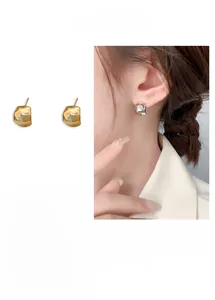 Macro detail of geometric C-shaped 18K gold earrings with molten lava texture