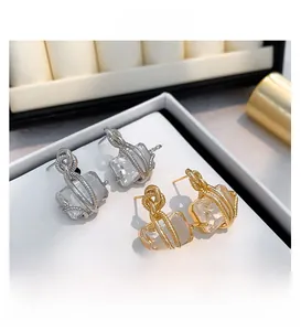 Détails macro de boucles d'oreilles torsadées dorées et argentées avec zircons carrés