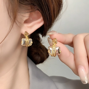 Détail de boucles d'oreilles dorées torsadées avec un grand zircon transparent pur