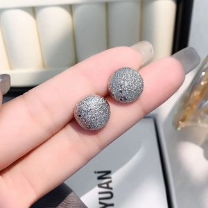 Minimalist silver round stud earrings with sparkling textured finish shown in a close-up