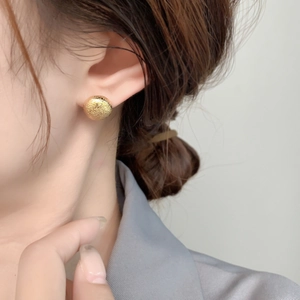 Minimalist gold textured round stud earring with a matte hammered finish on model