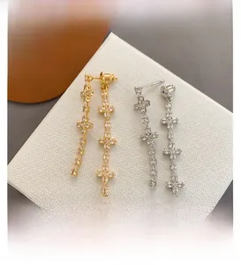 Detail showing long tassel drop earrings with cross stars and sparkling zircon stones