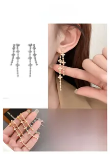 Macro detail of elegant clover cross tassel earrings with gold plating and zircons