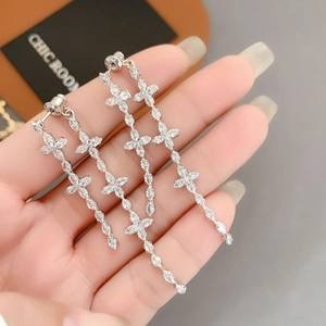 Close-up of silver tassel earrings with zircon-set cross elements and dangling chain