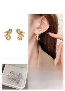 Macro view of 18K gold plated snake stud earrings with pavé crystals and black stone eyes