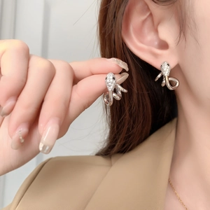 Detailed macro view of crystal-encrusted snake earrings in polished silver finish