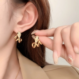 Close-up of gold snake earrings with pave zircon detail worn by a model