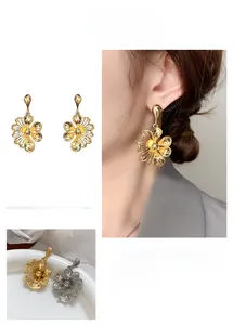 Detailed view of hollow flower earrings in gold and silver finish with petal design