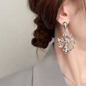 Macro detail of large floral silver earring with metallic petals on model's ear