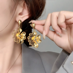 Elegant gold flower drop earrings for women with high-polish finish on a model