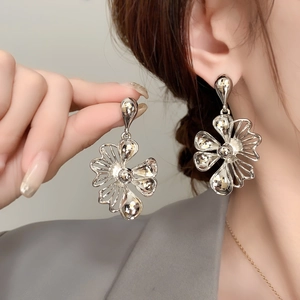 Silver hollow flower drop earrings in a layered petal design shown on a female model