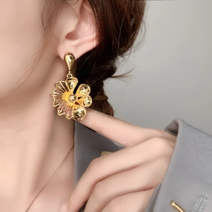 Close-up of elegant gold flower stud earrings worn by a model with a glossy metallic finish