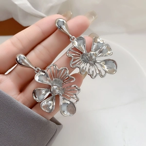 Detailed view of silver flower stud earrings with hollow petals in a stylish matte finish
