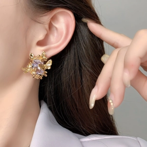 Boucles d'oreilles baroques en or avec papillon et zircon violet portées par mannequin