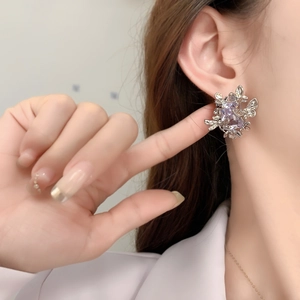 Boucles d'oreilles papillon en argent avec zircon mauve portées par un mannequin