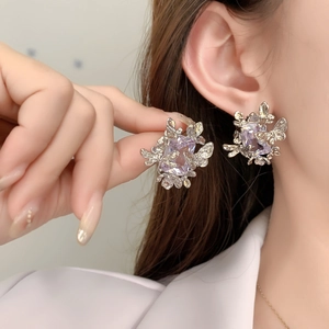 Détail de puce d'oreille argentée avec cristal carré violet et motifs papillons 3D