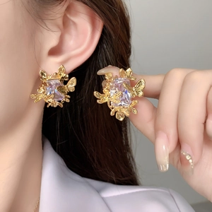 Détail de boucles d'oreilles papillon dorées avec un grand cristal rectangulaire et zircons