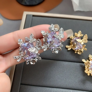 Gros plan de boucles d'oreilles dorées avec pierres violettes et détails papillons