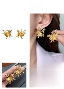 Detail of gold butterfly stud earrings featuring zircon accents and wavy textured wings