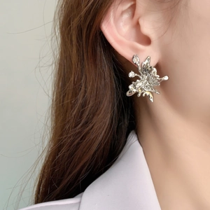 Detail of silver irregular flower stud earring with zircon core on a model ear