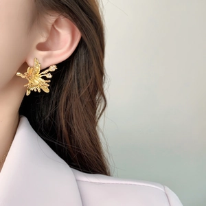 Macro shot of gold butterfly ear studs with sparkling zircons worn by a female model