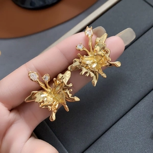 Macro shot of gold-plated fluid metal flower earrings with sparkling zircon accents
