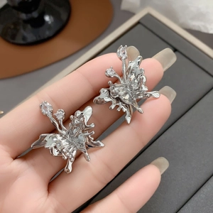 Detailed macro of silver butterfly earrings with liquid metal texture and zircon stones
