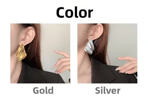 Dettaglio di grandi orecchini a perno ondulati color oro e argento indossati da una modella