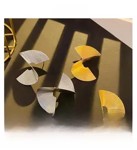 Detailed view of spiral fan-shaped earrings with fine radial textures in gold and silver