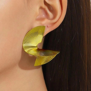 Detail of oversized gold spiral pleated fan earrings on model for a bold fashion look