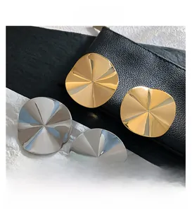 Detailed close-up of irregular textured gold and silver plated metal stud earrings
