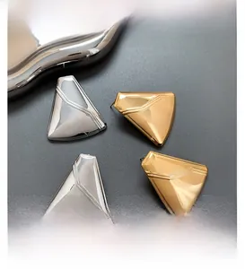 Detail of geometric shield-shaped stud earrings in polished gold and silver finishes