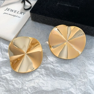 Detail of gold-plated earrings with irregular disc shape and radial wave texture