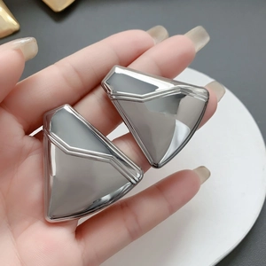 Macro shot of silver-colored geometric triangle earrings with a modern polished finish