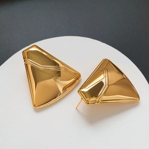 Close-up of geometric triangle gold-plated stud earrings with mirror polished finish