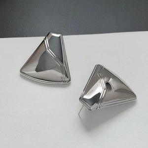 Close-up of geometric triangle silver earrings with mirror polish and tiered line details