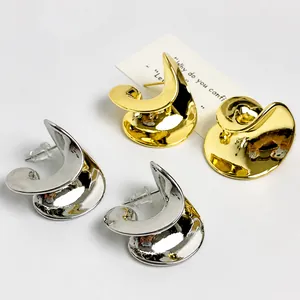 Close-up of polished gold and silver wave-shaped stud earrings in abstract spiral design