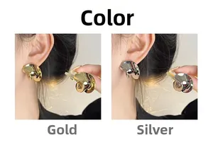 Detalle de pendientes de botón de metal retorcido en oro y plata en modelo y mano