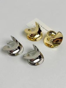 Detalle macro de pendientes en espiral dorados y plateados con acabado de espejo