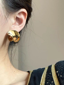 Detalle de pendiente de cuenco bañado en oro con cuenta de ámbar en la modelo